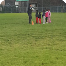 a group of children having soccer practice and listening to their coach